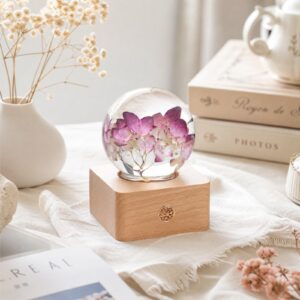 Red hydrangea lamp with preserved flowers in a clear resin sphere on a beech wood LED base, styled as romantic bedroom decor