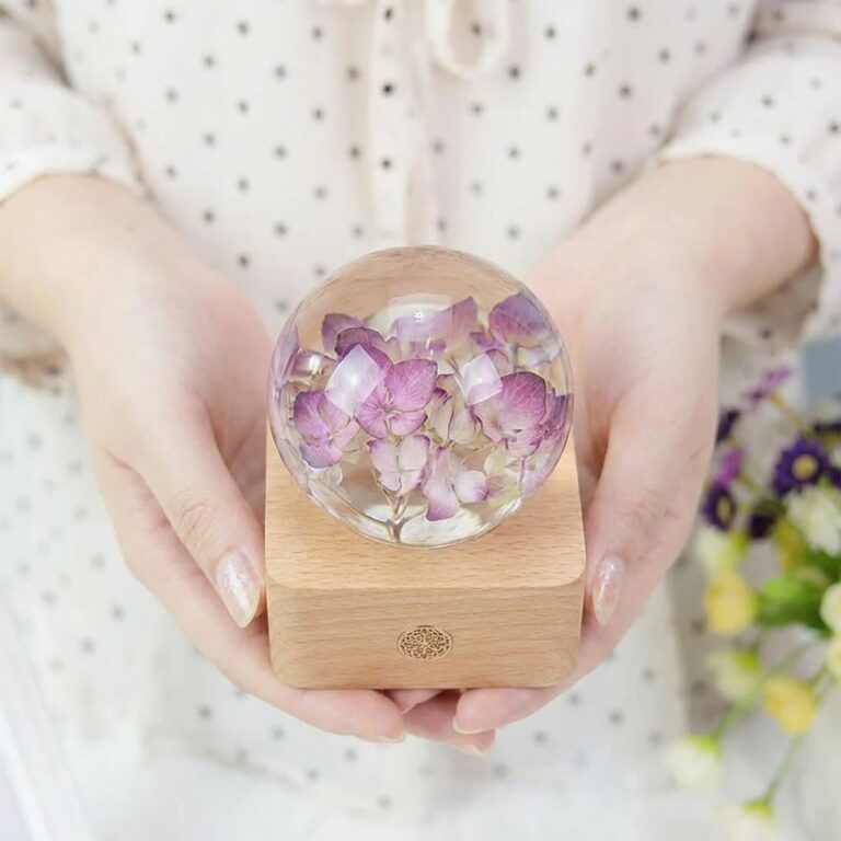 Close-up of a preserved flower held in a clear resin sphere on a beech wood base