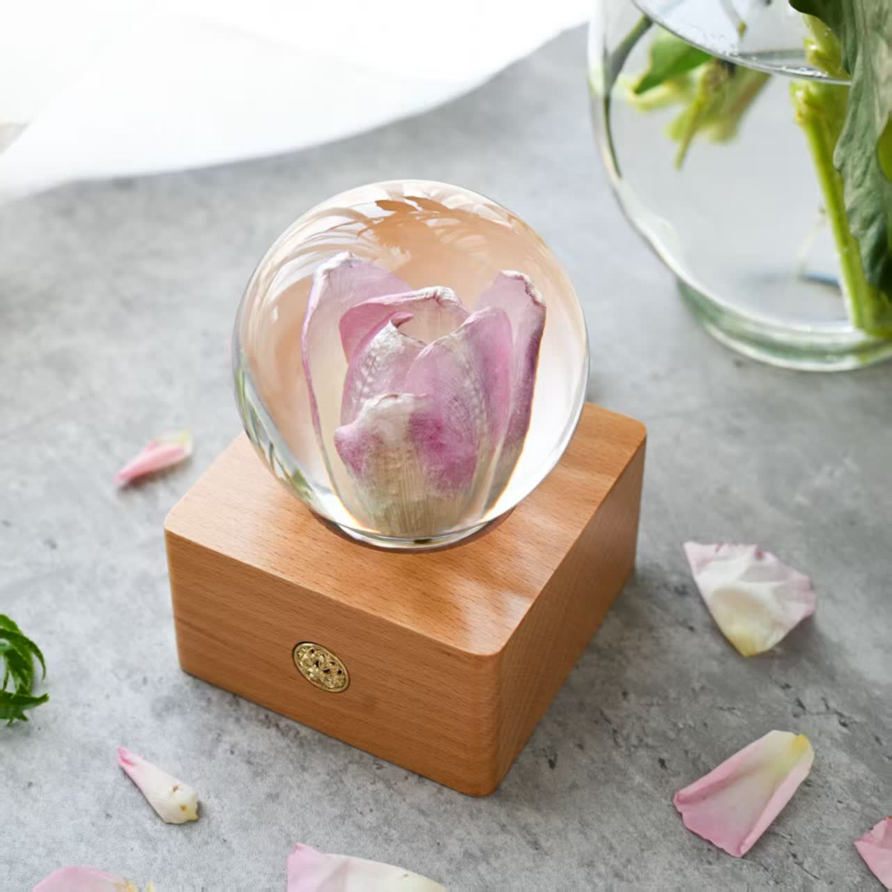 Pink purple tulip flower lamp on a tabletop with petals, clear resin sphere and warm wooden base